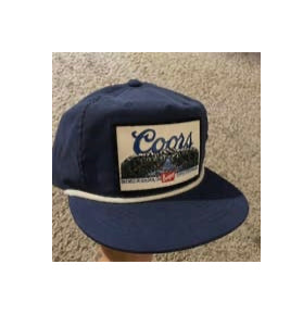 A navy blue baseball cap with "Coors" written across the top and followed by scenery underneath.