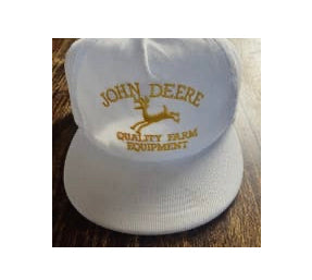 A white baseball cap with the John Deere logo in gold. 