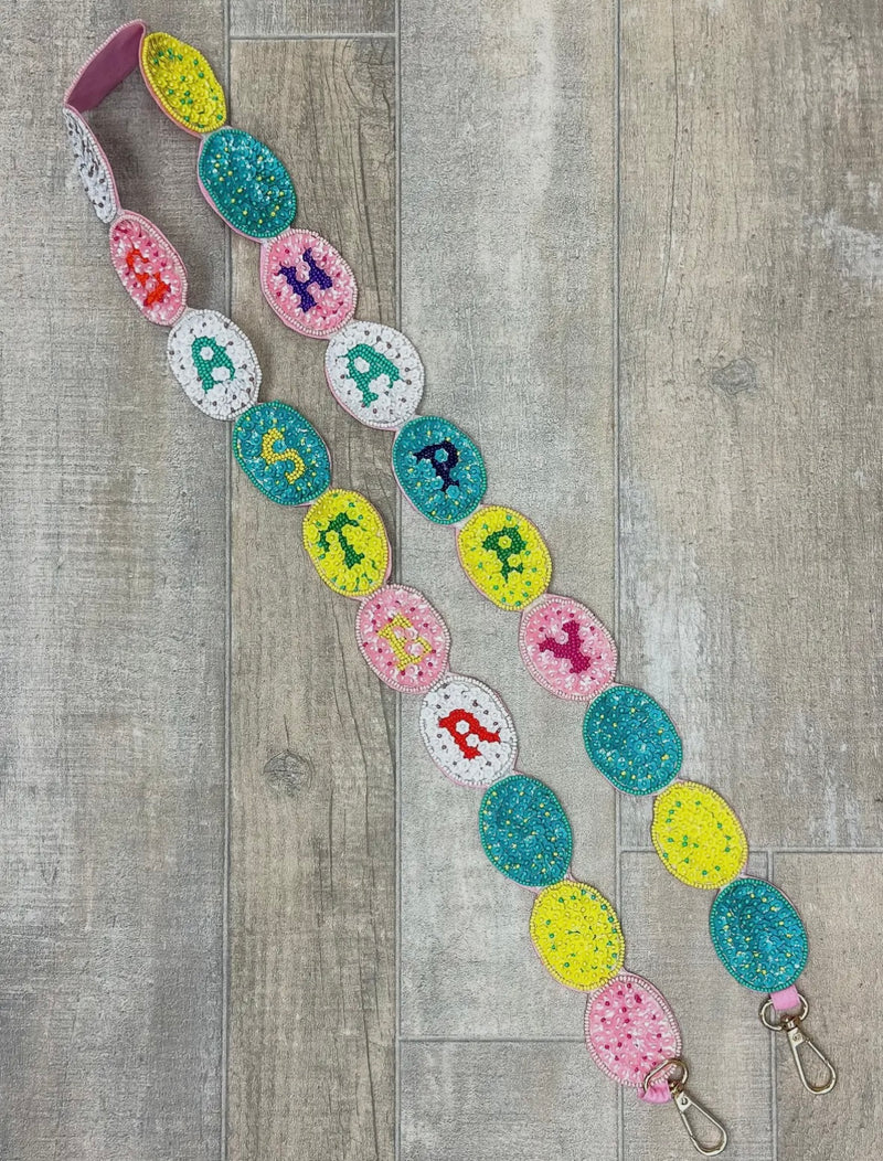 A multicolored sequin purse strap with "happy easter" spelled down the sides.