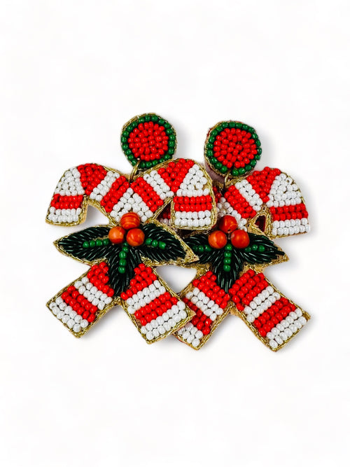 A pair of beaded earrings in the shape of two candy canes crossing and mistletoe in front.