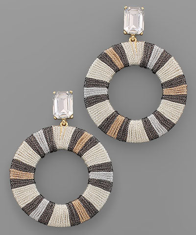 A pair of dangling earrings that are neutral stripes in a hollow circle.