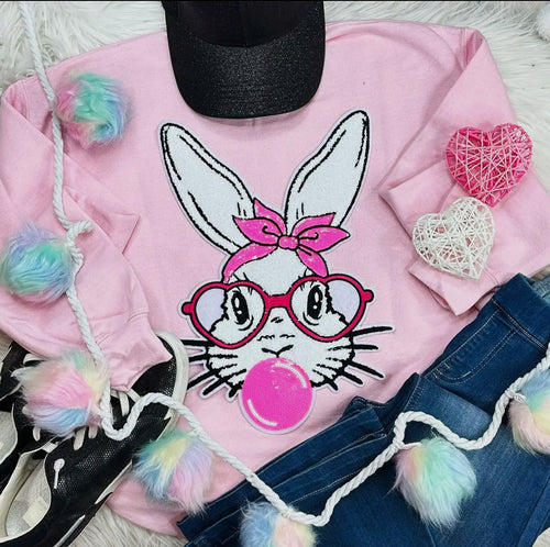 A light pink crewneck sweatshirt with a bunny face patch on the front.