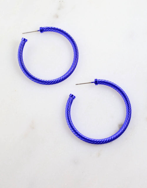 A pair of large blue hoops that have a spiral texture.