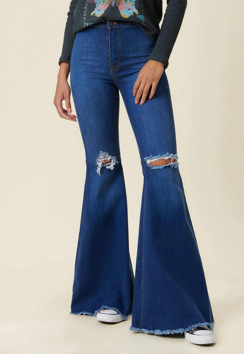 A pair of dark wash, high-waisted flare jeans with medium-sized holes in the knees and a frayed hem.
