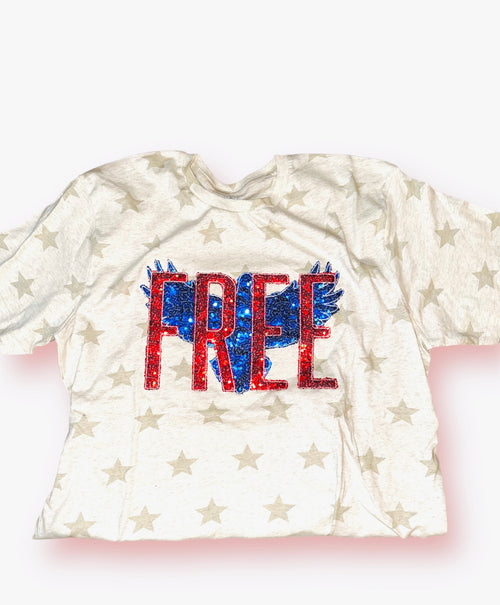 A cream heathered t-shirt with tan starts and a blue sequin bird with "free" on top in red sequins.