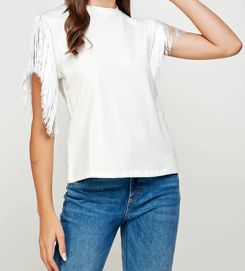 A white short sleeve blouse with fringe detailing on the sleeves and a high neck.