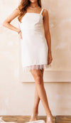A white textured mini dress featuring thick straps and beaded fringe detailing on the bottom hem.
