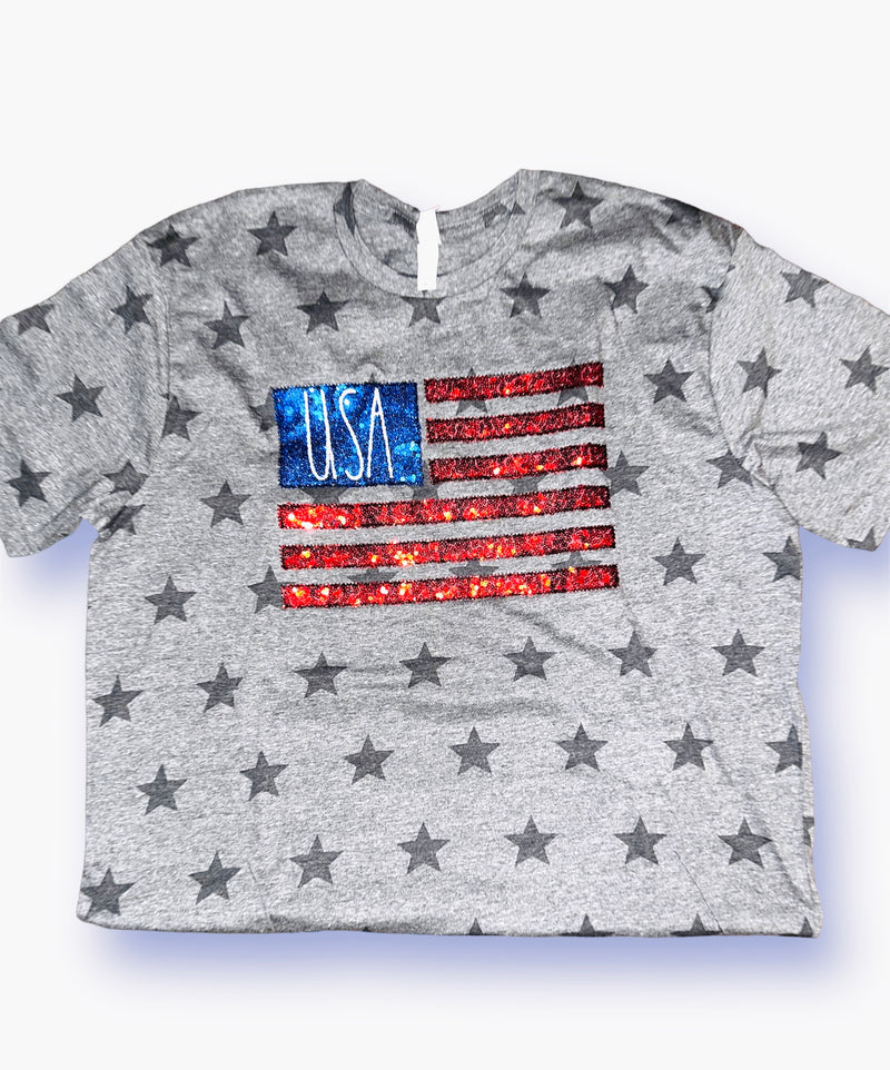 A light heather grey t-shirt with dark grey stars and a sequin patch of the American flag.