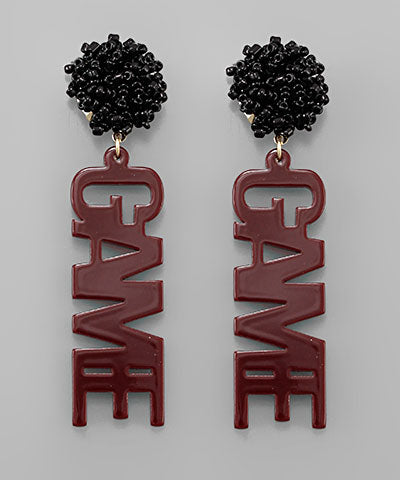 A pair of maroon and black earrings that say "game".