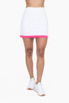 A high-wasited white mini tennis skort with a neon pink stripe around the bottom hem.