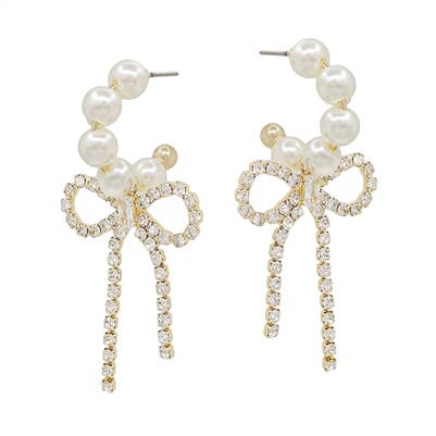 A pair of pearl hoops with a rhinestone bow dangling. 