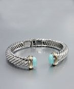 A silver bracelet cuff with a rope texture and teal stones on the end.