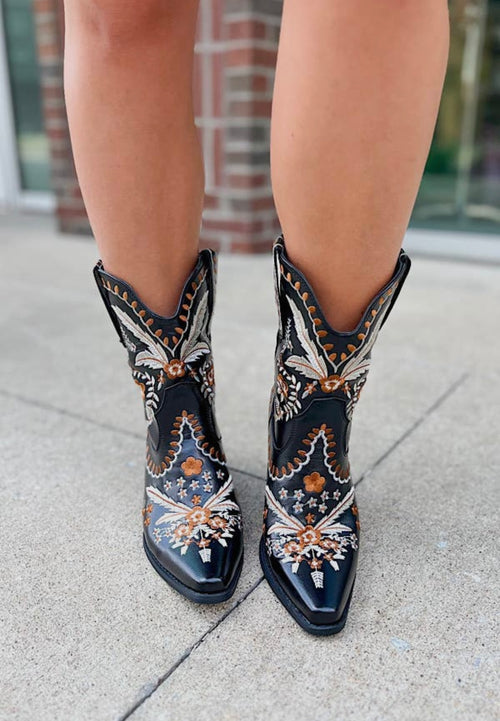 A pair of mid-rise cowboy boots in black leather with a neutral western pattern throughout.