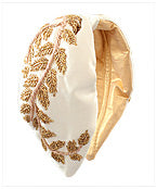 A white wide headband with gold leaf detailing throughout.