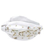 A white wide headband with "mama" written in gold patches along the side. 
