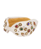 A white wide headband with multicolored jewels along the sides.