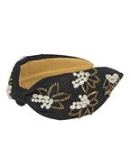 A black wide headband with a tan and pearl floral print.