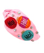 A Christmas themed headband with a pink fabric and multicolored ornament patches with "Ho!" on each of them.
