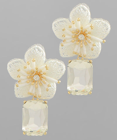 A pair of ivory dangling earrings with a flower stud and crystal pendant.