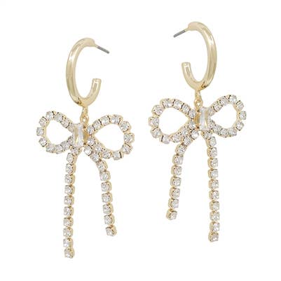 A pair of dangling gold earrings which feature a rhinestone bow. 