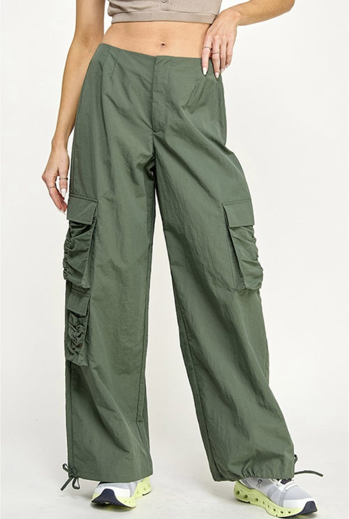 A pair of army green parachute pants with cargo pockets and a mid-rise waist.