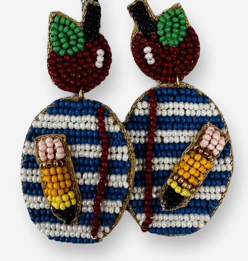 A pair of school themed beaded earrings featuring an apple, notebook, and pencil. 