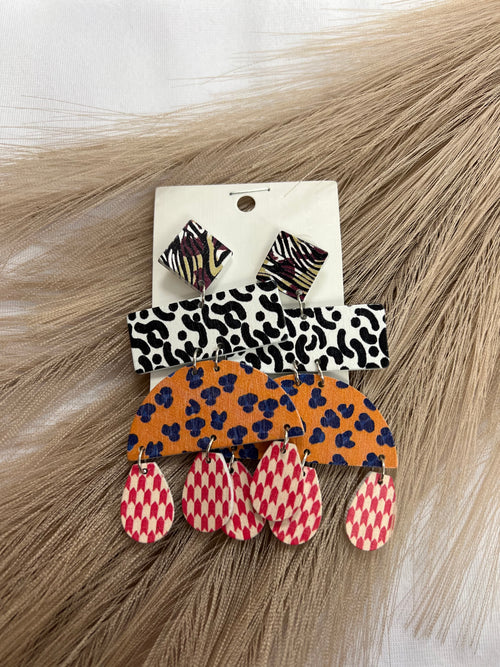 A pair of dangling wood earrings featuring different shapes and prints. 
