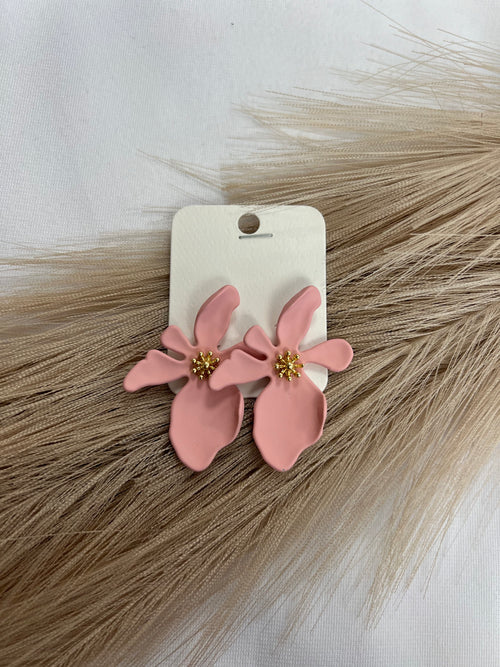 A pair of pink earrings in the shape of asymmetrical flowers with gold detailing.