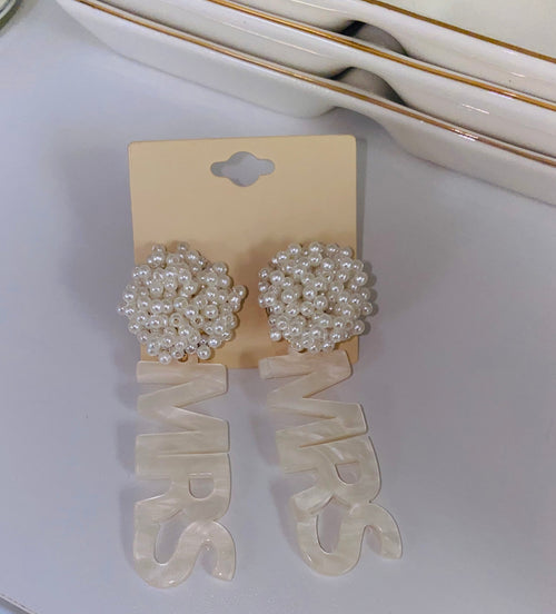 A pair of pearl dangling earrings with "mrs" on each of them.