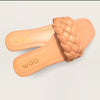 A pair of nude flat sandals with a braided style strap across the toes.