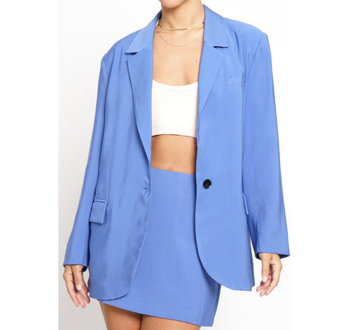 A sky blue oversized blazer featuring a black button and multiple pockets.