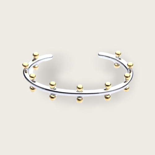 A silver cuff with gold ball studs throughout.