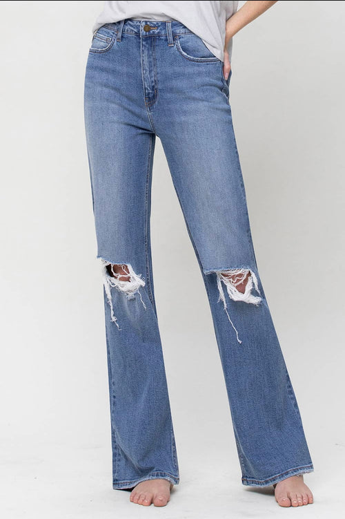 A pair of high-waisted medium wash jeans featuring a wide leg and rips in the knees.