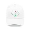 A white baseball cap with a green line drawing of pickleball paddles and a small pink heart above them.