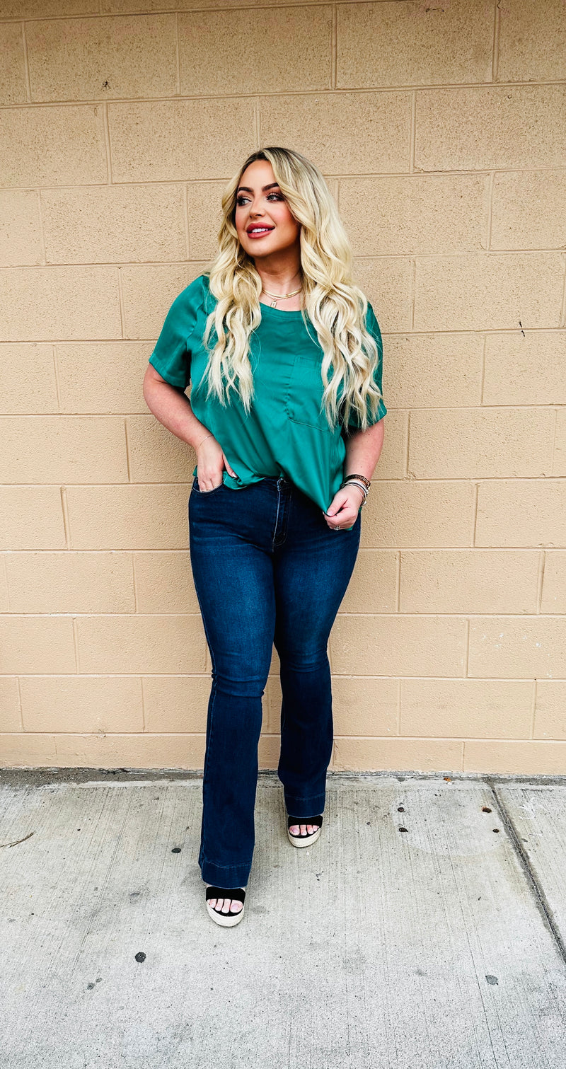 An emerald green satin short sleeve blouse with a pocket. 