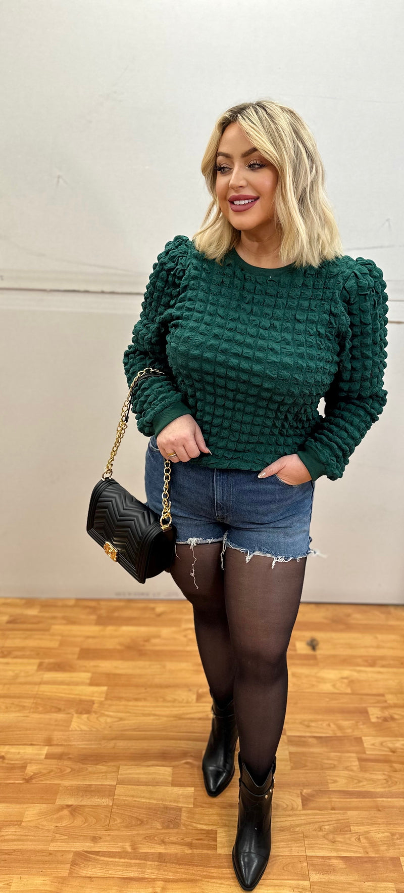 An emerald green sweater with a quilted texture and puff sleeves. 