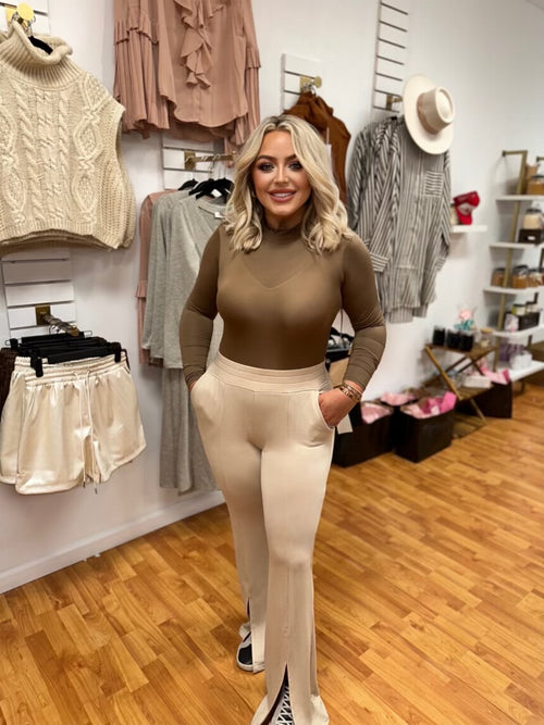A light brown bodysuit with a mock neck and long sleeves. 