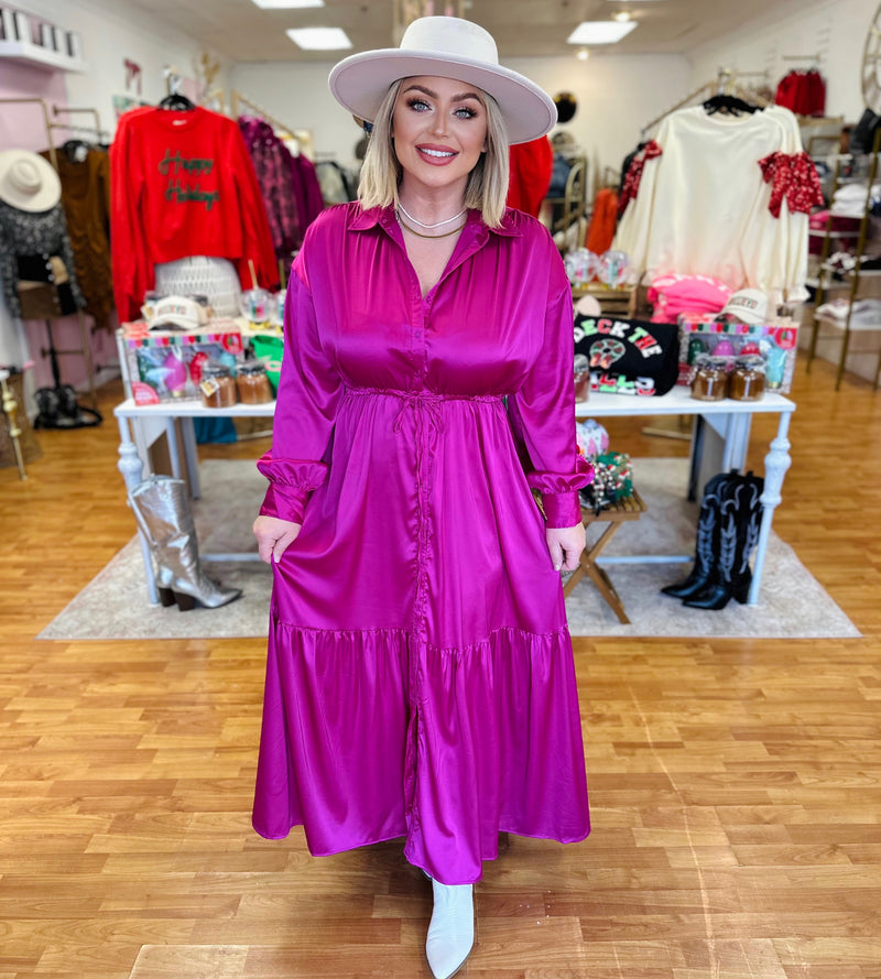 A magenta satin button down maxi dress featuring long sleeves, a collar, and a loose fit