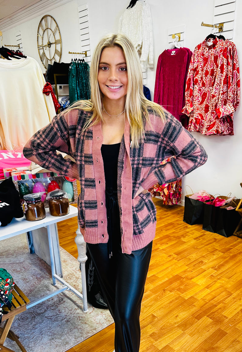 A pink and black plaid cardigan with buttons.