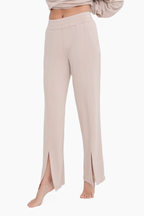 A pair of beige lounge pants featuring a white leg with a split hem and a high waist.