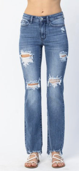 A pair of medium wash, distressed jeans with multiple holes throughout and a frayed hem. 