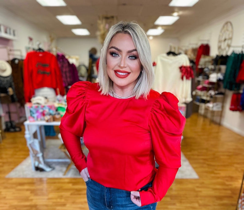 A bright red satin long sleeve blouse with puff sleeves. 