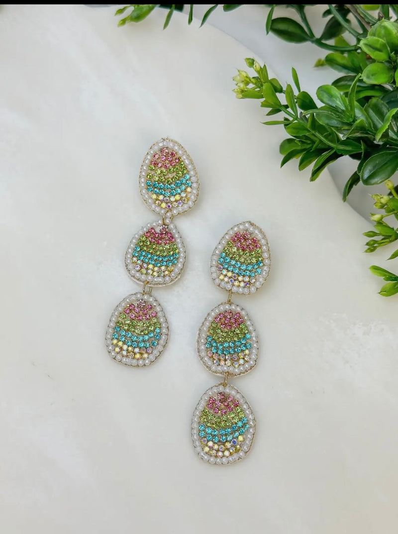 A pair of beaded dangling earrings in the shape of multicolored Easter eggs stacked on top of each other. 