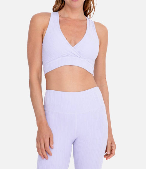 A light purple textured sports bra with a v-neckline and crossover detailing. 