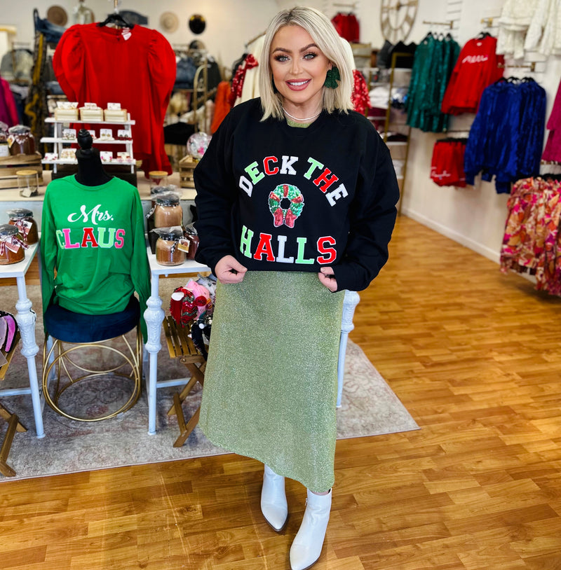 A black crewneck sweater reading "deck the halls" in red, white, and green along with a Christmas wreath in the center.