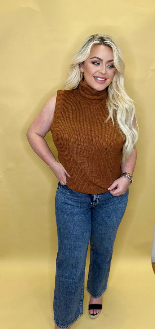 A sleeveless rust colored sweater with a turtleneck.