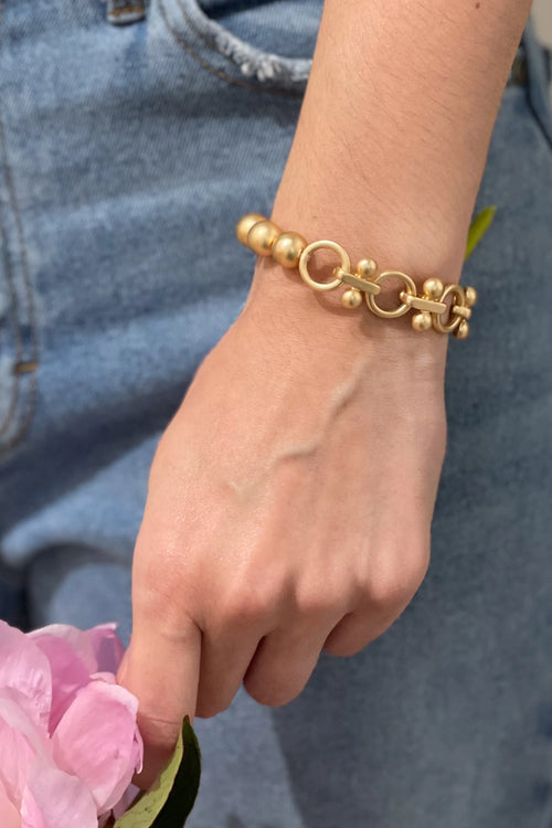 A gold chunky bracelet with different types of beading. 