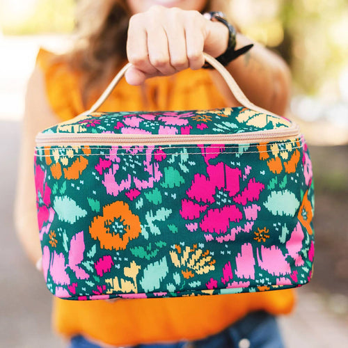 A large cosmetic bag in a turquoise, hot pink, and orange floral print and features a tan top handle.