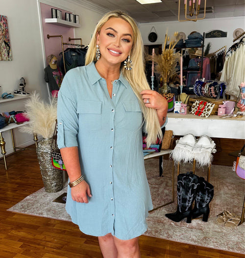 A light blue mini dress with buttons down the front, a collar, and quarter sleeves. 