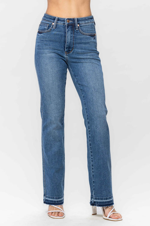 A pair of dark wash high-waisted jeans in a boot cut style and raw hem.